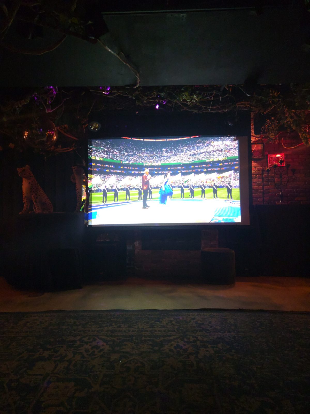 Large projector screen at a themed bar showing a live broadcast